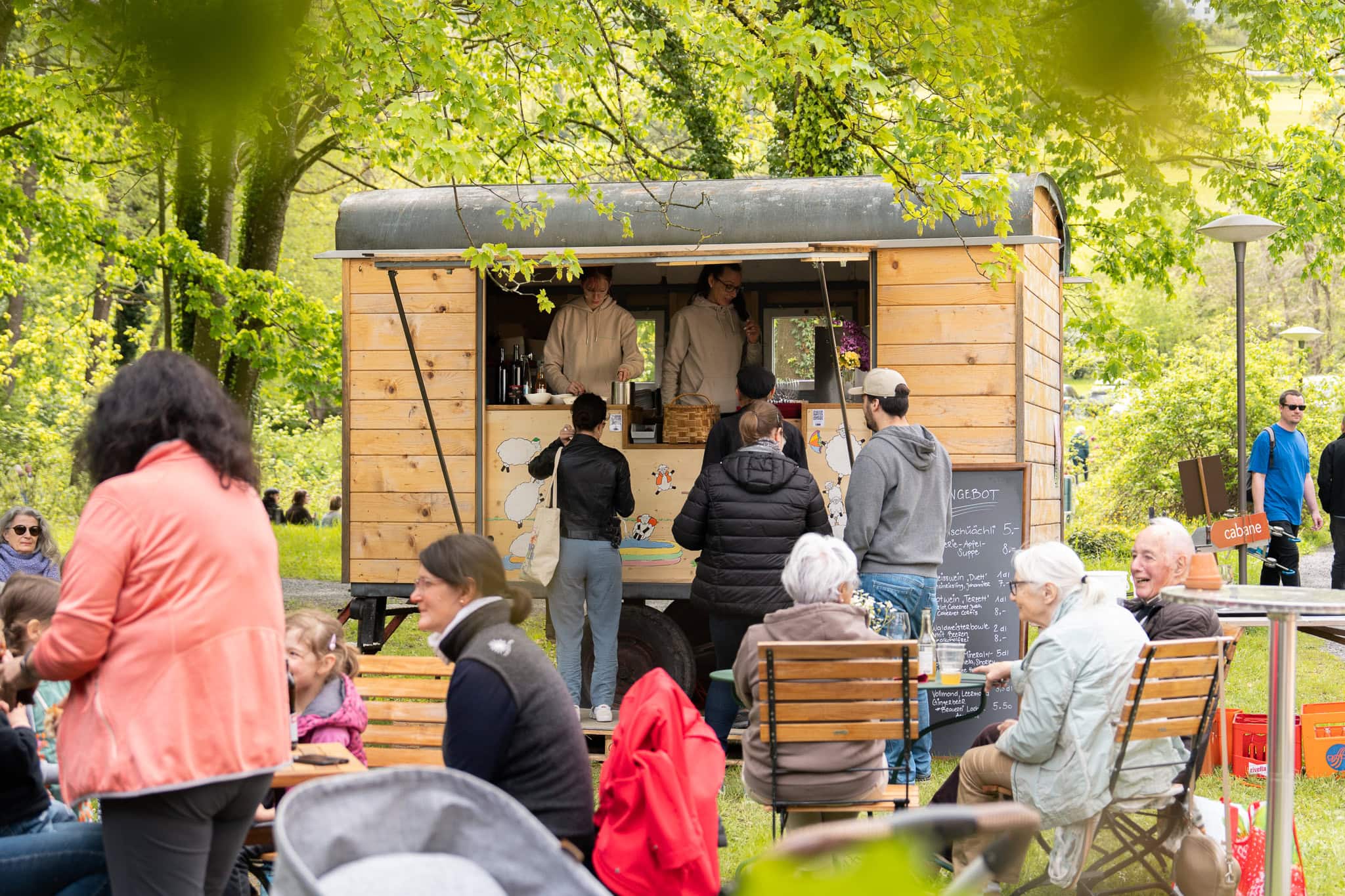 Kaffeewagen im Park mit fröhlichen Besuchern.